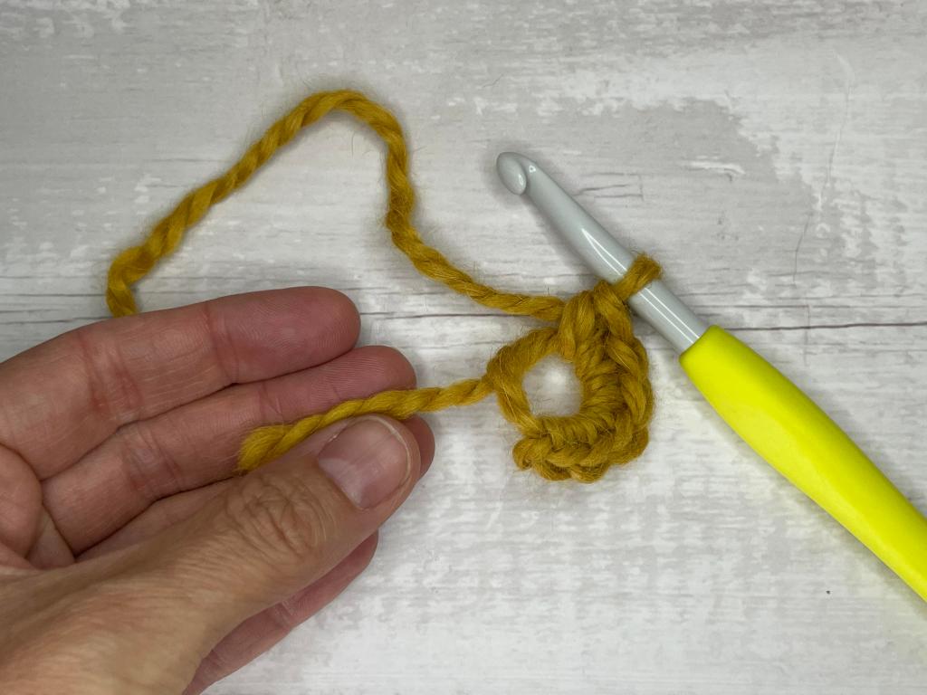 step by step photos illustrating how to make a magic circle crochet stitch